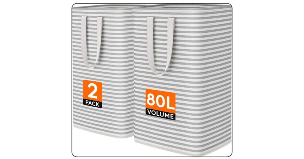 Two grey collapsible laundry hampers in small dorm room corner one upright full of clothes and one folded flat showing space saving design