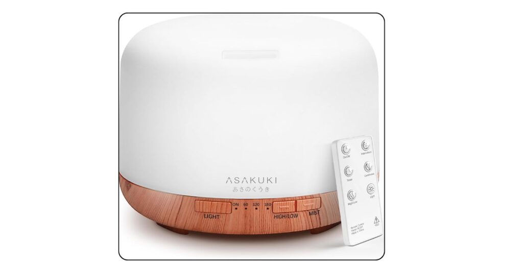 Small white essential oil diffuser humidifier on college dorm desk at night with soft blue purple LED glow and light mist visible