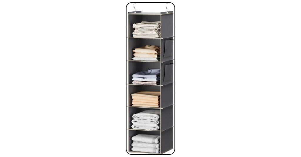 Grey fabric hanging closet organizer installed on dorm room closet rod with six shelves of neatly folded clothes and hanging clothes above