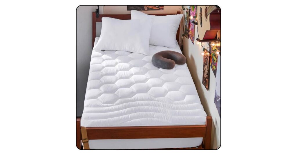 Twin XL mattress topper on neatly made dorm bed with white quilted fabric soft pillows and warm morning light from window
